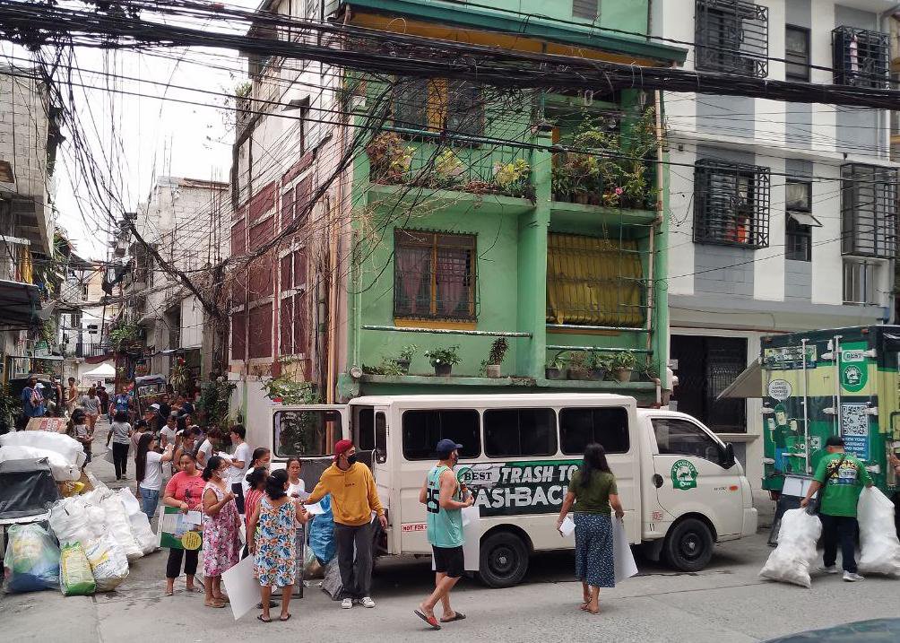 A Trash to Cashback van collecting sorted recyclables on a dense city street
