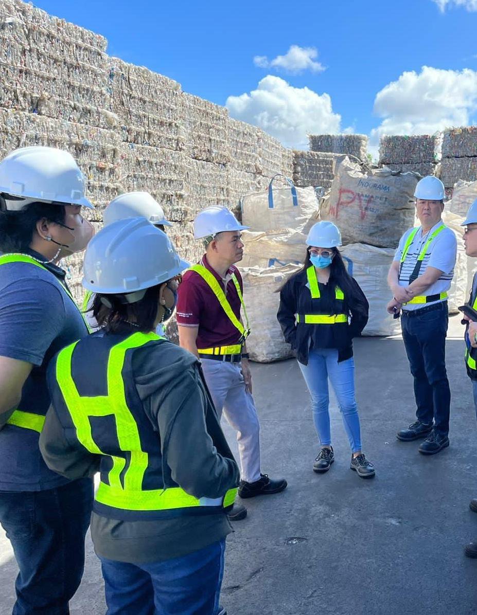 Team in hard hats before baled recovered paper at a recycling facility