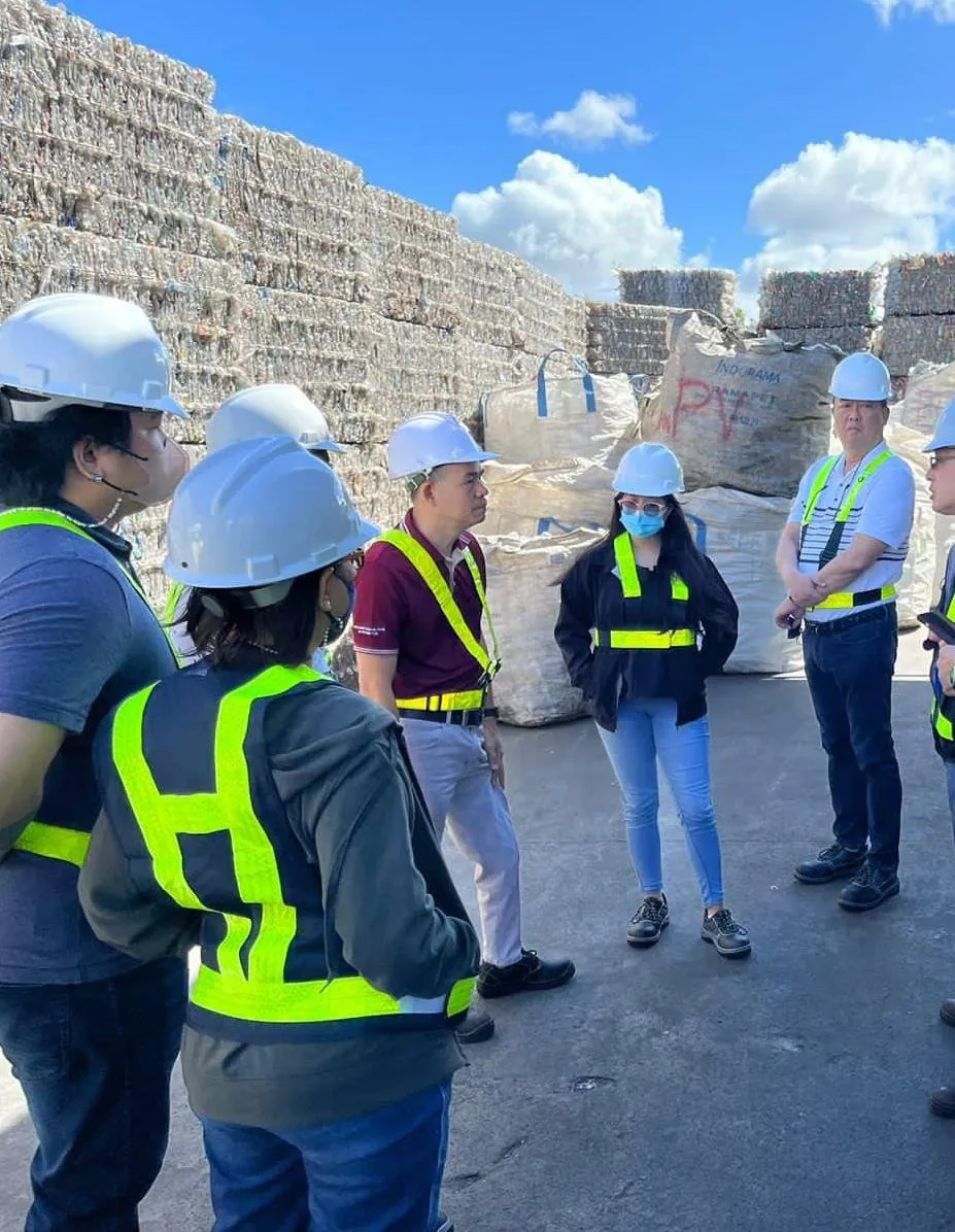 Team in hard hats before baled recovered paper at a recycling facility