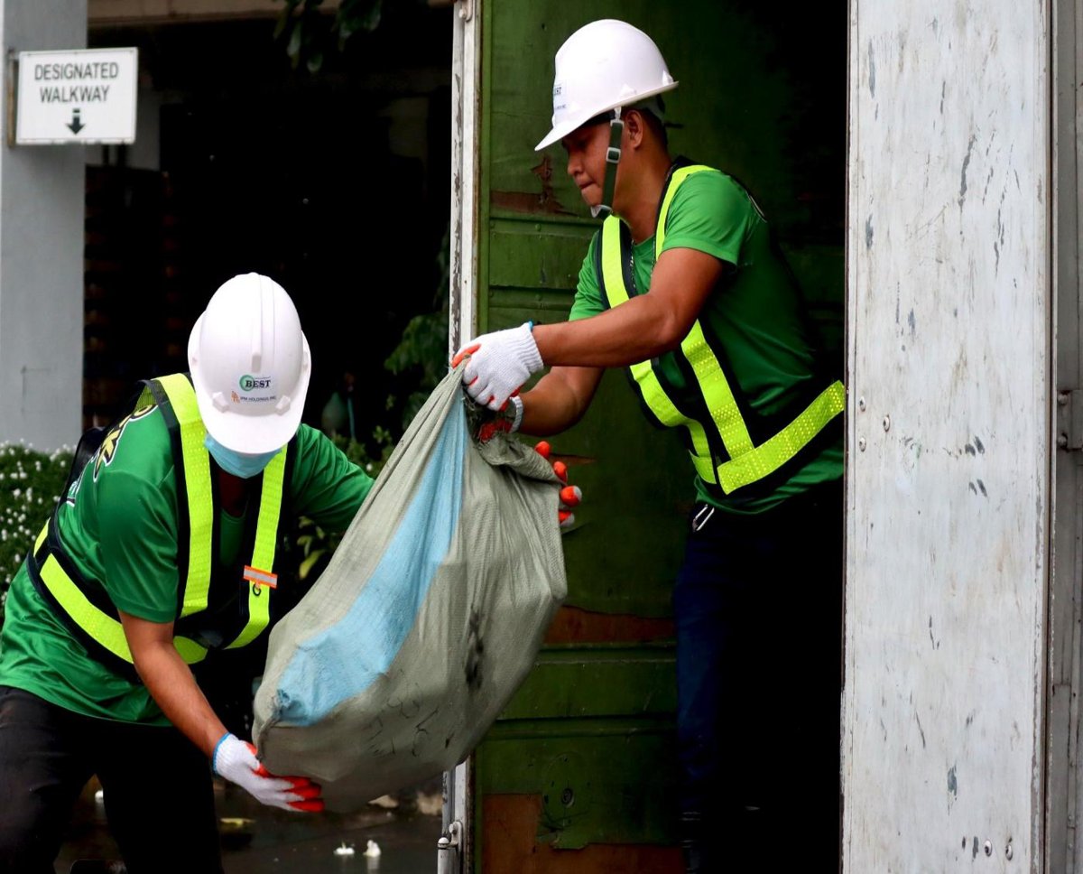 BEST crew in hard hats receiving a sorted bag at a doorway collection point